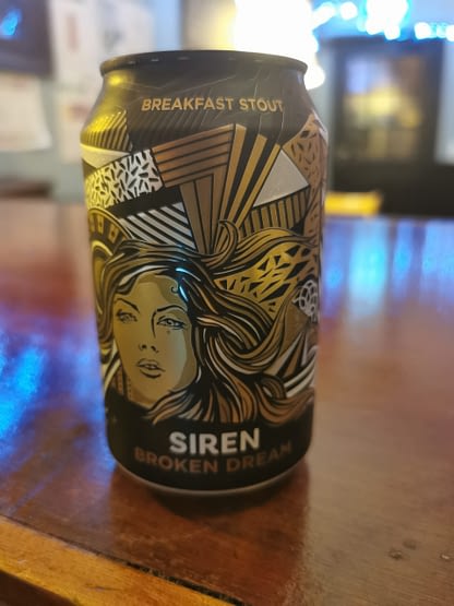 Dark can with a woman's face in gold & decorative lines and stripes surrounding it