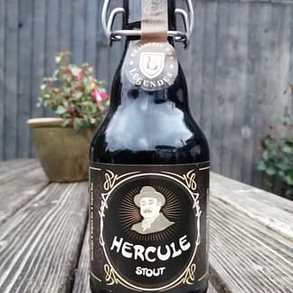 Dark brown flip top stubby bottle on the slat of a wooden picnic bench, label depicts Hercule Poirot.